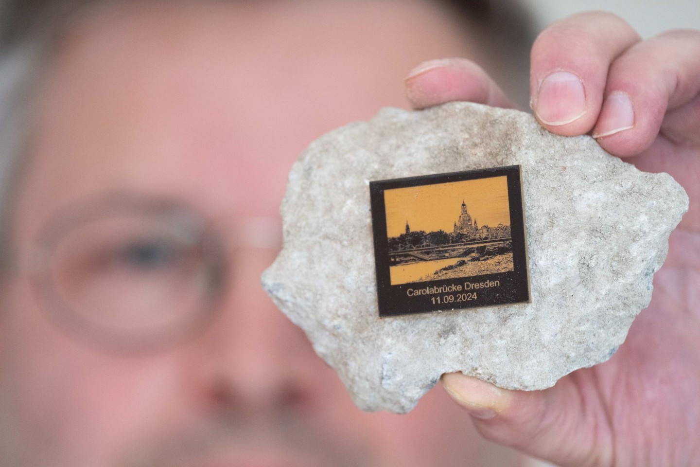 Torsten Daae, Geschäftsführer im Dresdner Laden «Catapult», hält einen Stein des abgerissenen Brückenteils der eingestürzten Carolabrücke mit einer Plakette in der Hand.